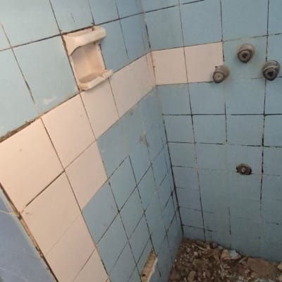 קיר אריחים שבור עם הריסות על הרצפה