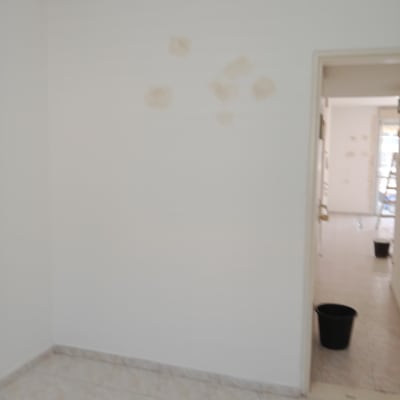 קיר עם תיקוני צבע ודלי שחור בחדר ריק