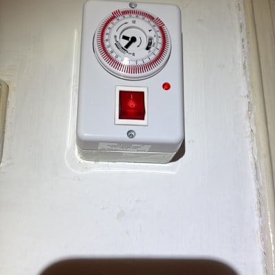 טיימר חשמלי מותקן על קיר עם נורית חיווי אדומה