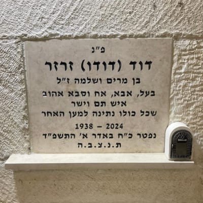 מצבה עם כיתוב בעברית ותמונה של נר זיכרון