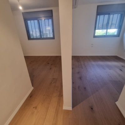 חדר ריק עם רצפת עץ וחלונות עם תריסים