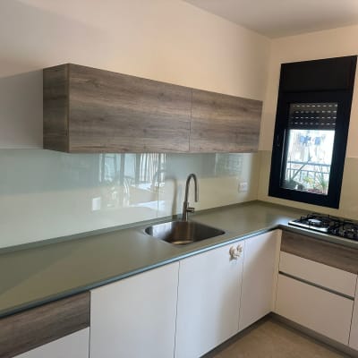 מטבח עם חיפוי זכוכית מעל השיש והכיור