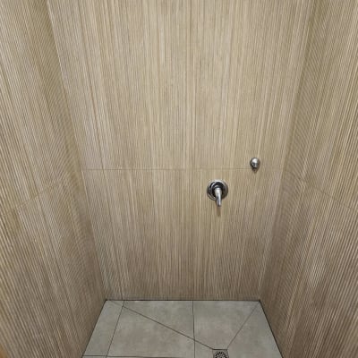 חדר מקלחת עם אריחים חומים וברז מותקן