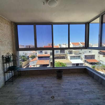 מרפסת סגורה עם חלונות זכוכית ונוף לבניינים