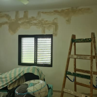 סולם עץ ליד קיר עם תיקוני טיח