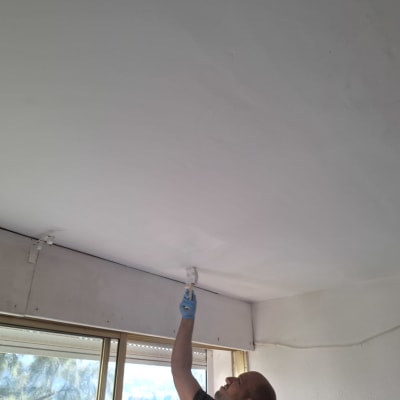 אדם צובע תקרה עם רולר צבע