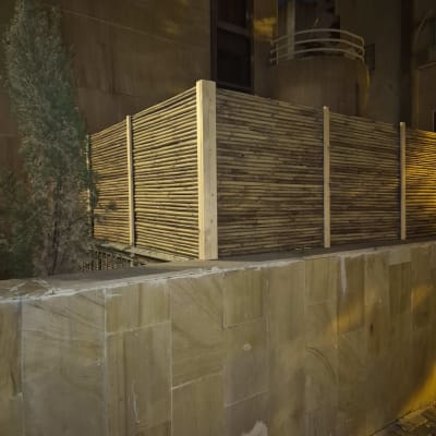 גדר עץ במבוק ליד קיר אבן