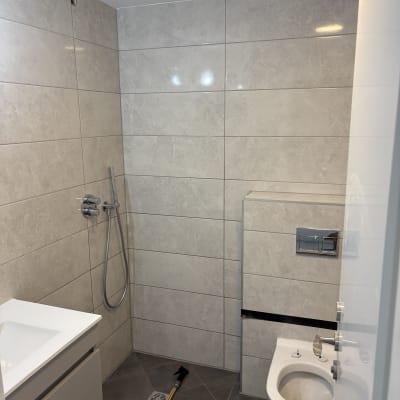 חדר אמבטיה עם קירות אריחים, כיור ואסלה