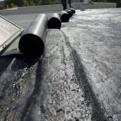 רולקות איטום על גג עם אדם בעבודה