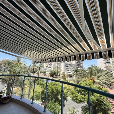 מרפסת עם סוכך בד פסים ונוף עירוני