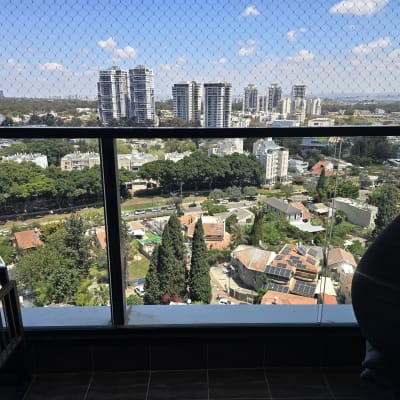 נוף עירוני עם מרפסת זכוכית ורשת בטיחות