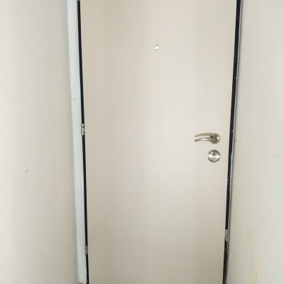 דלת לבנה עם ידית מתכת ומגן רצפה