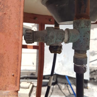 שסתום מתכת חלוד על דוד שמש עם צינורות מחוברים