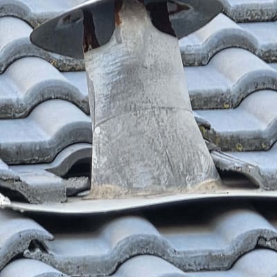 ארובה על גג רעפים כחולים עם חלודה קלה