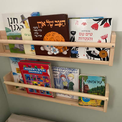 מדפי עץ עם ספרים לילדים על הקיר