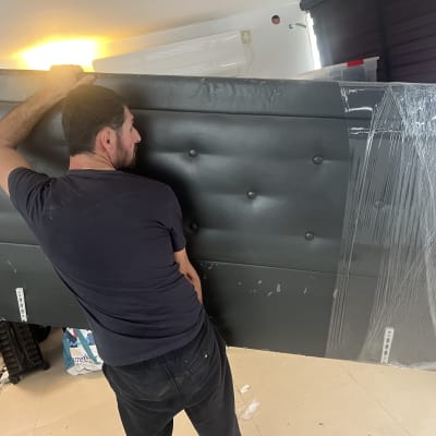 אדם נושא ראש מיטה עטוף בניילון