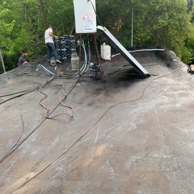 אדם עובד על איטום גג עם יריעות ביטומניות.