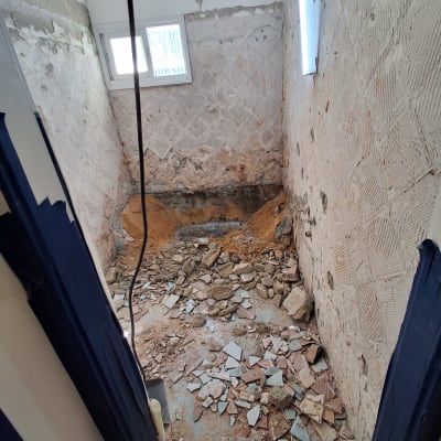 חדר בשיפוץ עם קירות חשופים ופסולת בנייה על הרצפה