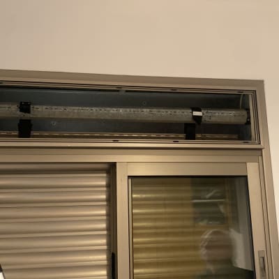 תריסים וחלון עם מנגנון פתיחה על קיר לבן