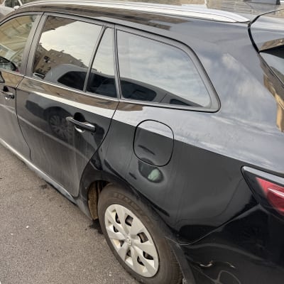 חלון אחורי של רכב שחור עם השתקפות בניינים