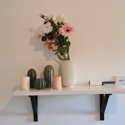 מדף תלוי עם תומכים שחורים על קיר לבן