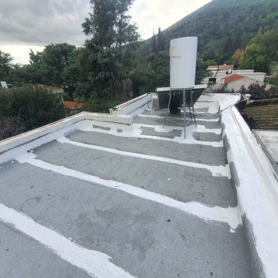 איטום גג עם חומר לבן על משטח אפור