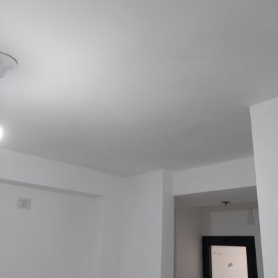 קירות ותקרה צבועים בלבן עם חלון קטן