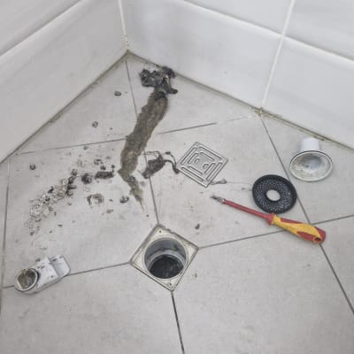 כלי עבודה וניקוז במקלחת לאחר פתיחת סתימה