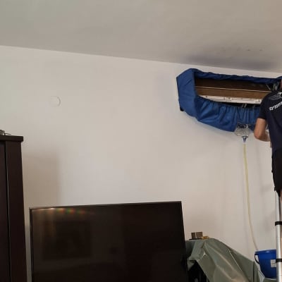 אדם על סולם מתקן מזגן בבית