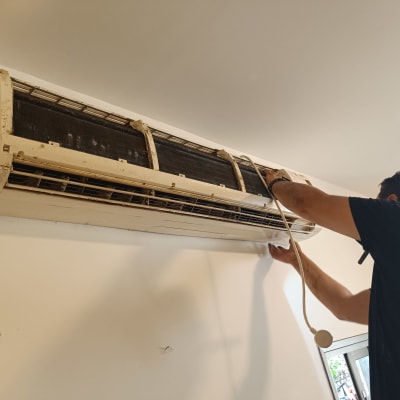 אדם מתקין מזגן על קיר פנימי