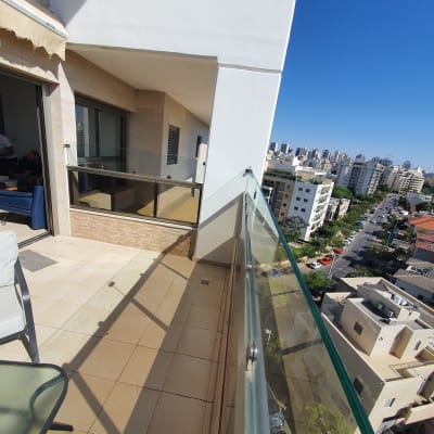 מעקה זכוכית במרפסת עם נוף עירוני