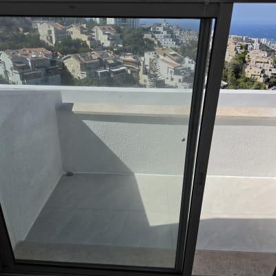 מרפסת מרוצפת באריחי גרניט פורצלן בהירים הצופה לנוף עירוני וים