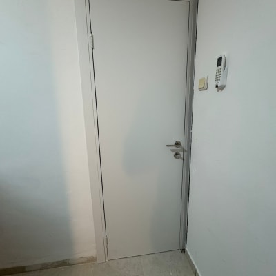 דלת לבנה עם ידית מתכת על קיר לבן