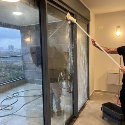 ניקוי חלונות עם מגב וסבון על מרפסת
