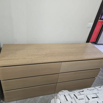 שידה מעץ ליד מיטה בחדר שינה