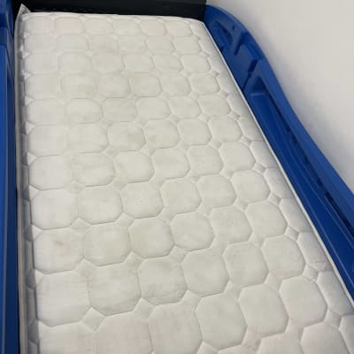 מזרן לבן בתוך מסגרת פלסטיק כחולה