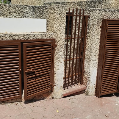 תריסים חומים על קיר חיצוני עם שביל מרוצף