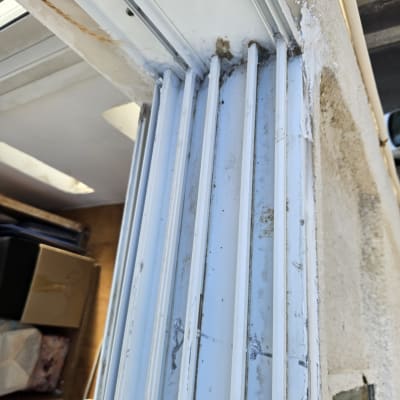 מסילות תריסים לבנות עם סימני לכלוך וקילוף צבע