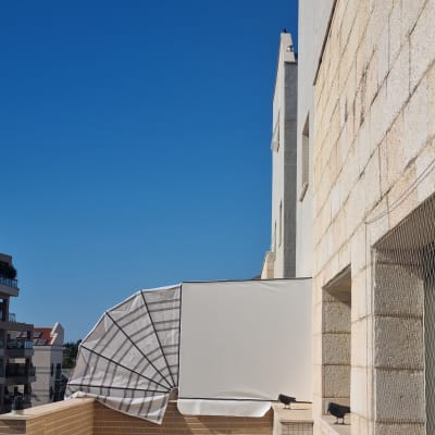 סוכך על מרפסת בבניין מגורים עם שמיים כחולים