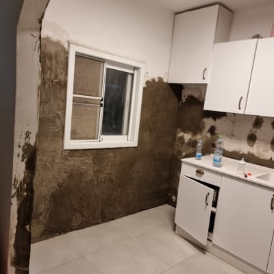 קיר מטויח, ארונות מטבח פתוחים, בקבוקי מים על השיש