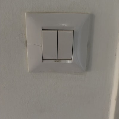 מתג חשמל על קיר לבן עם סדק קטן