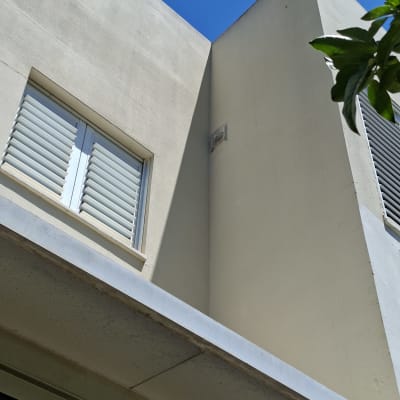 חזית בניין עם חלון ותריסים ביום שמש