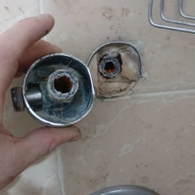 חלקי צנרת מתכתיים על קיר אמבטיה