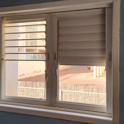 תריסים לבנים בחלון עם שלבים פתוחים וסגורים