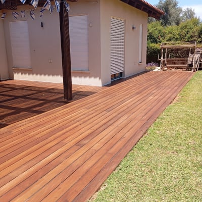 דק עץ חום ליד בית עם דשא ירוק