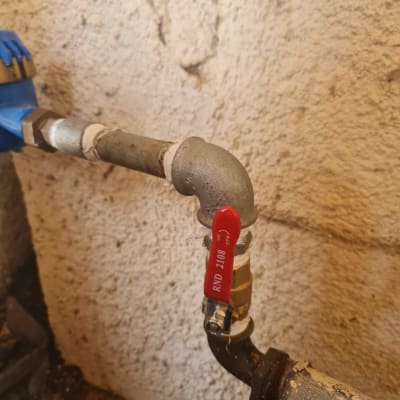 צינור מתכת עם ברז אדום על רקע קיר