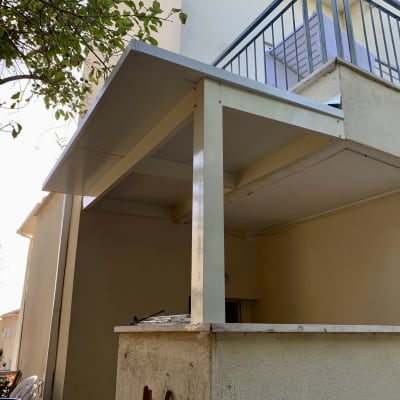 פרגולה מאלומיניום מחוברת לקיר חיצוני של מבנה
