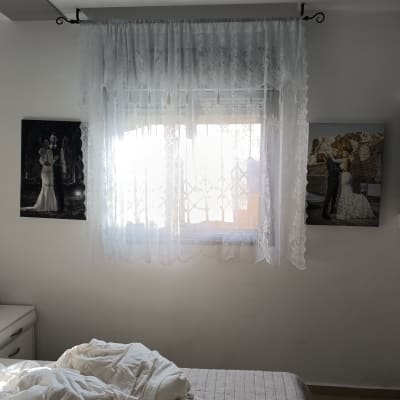 חדר שינה עם וילון לבן ותמונות על הקיר