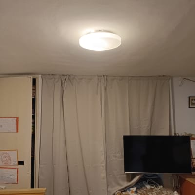 מנורה מותקנת על תקרה בחדר עם וילון וטלוויזיה