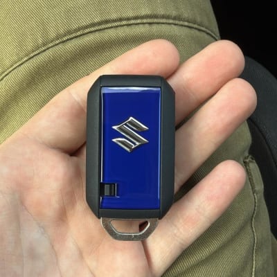 מפתח רכב סוזוקי ביד על רקע מכנסיים ירוקים